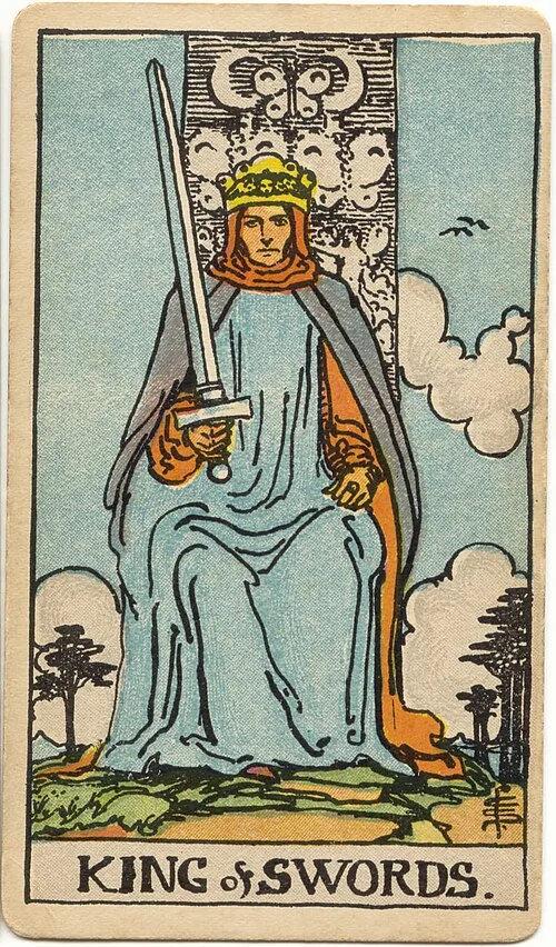 Rei coroado e vestido de azul está sentado de frente, com uma espada inclinada à esquerda de quem observa e trono ornamentado.